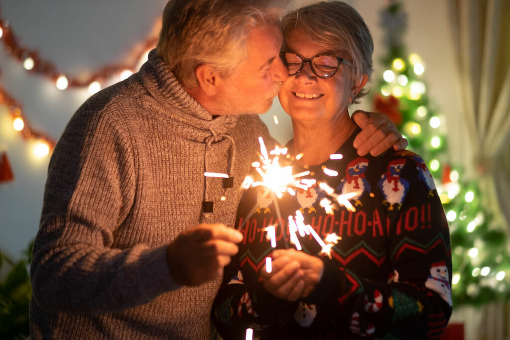 The Philomena | Senior couple holding a sparkler at next to a Christmas tree